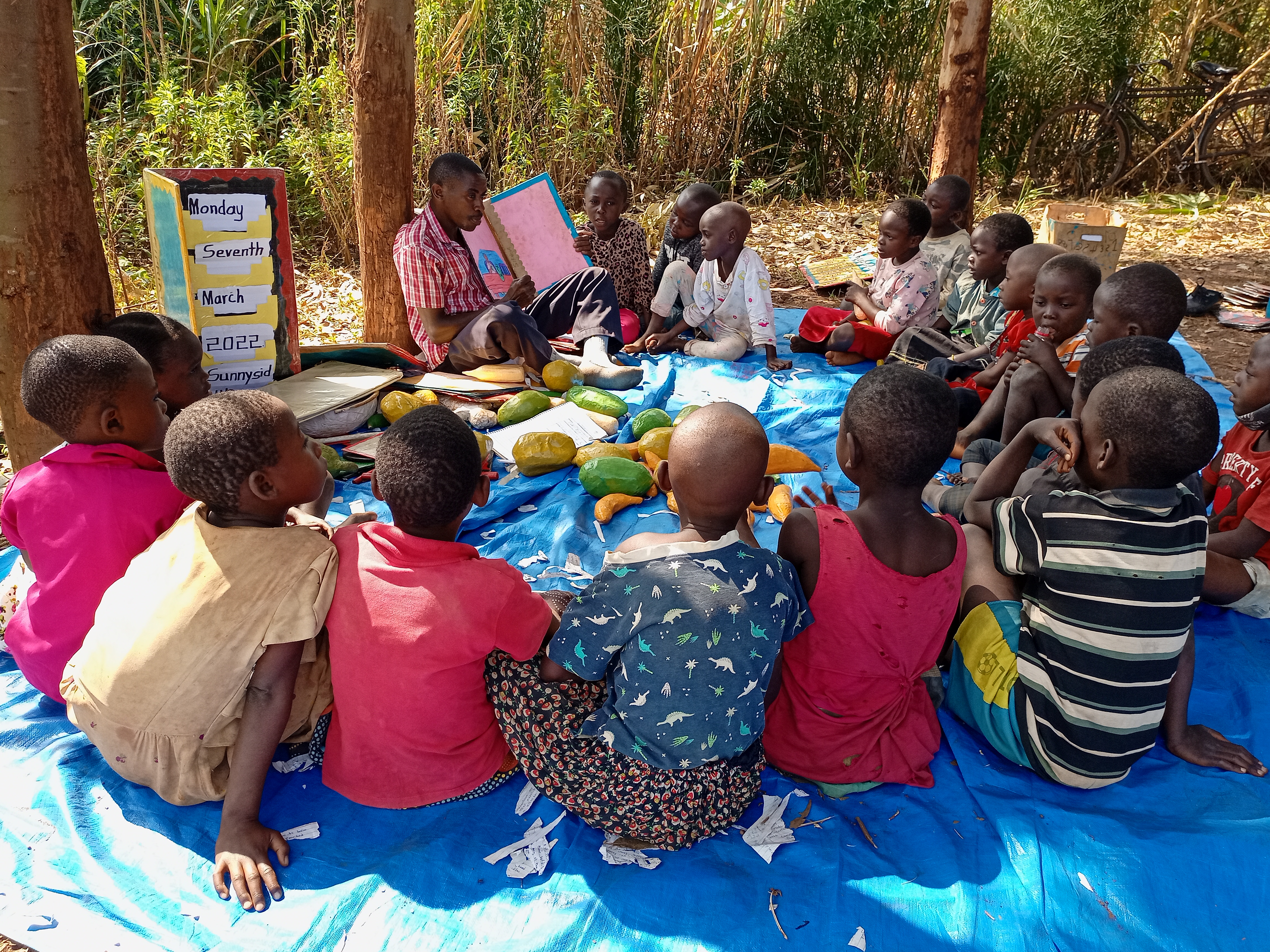 YESRA teacher leading an outdoor learning session with children in Kyaka II, Uganda